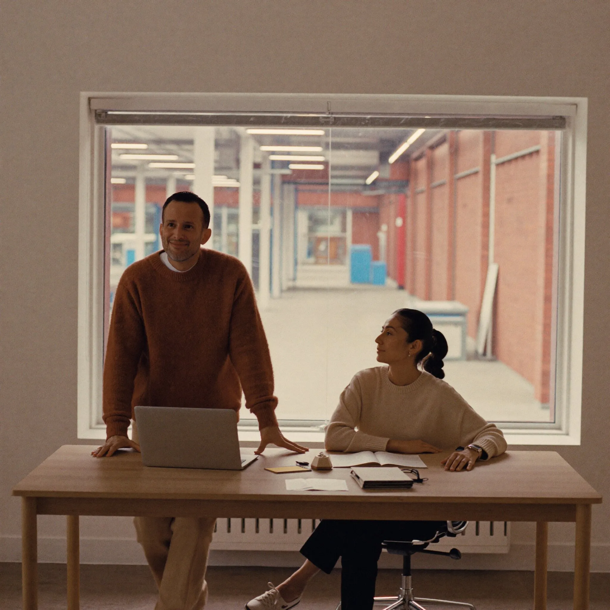 Two plant operations leaders in a modern office overlooking the factory floor