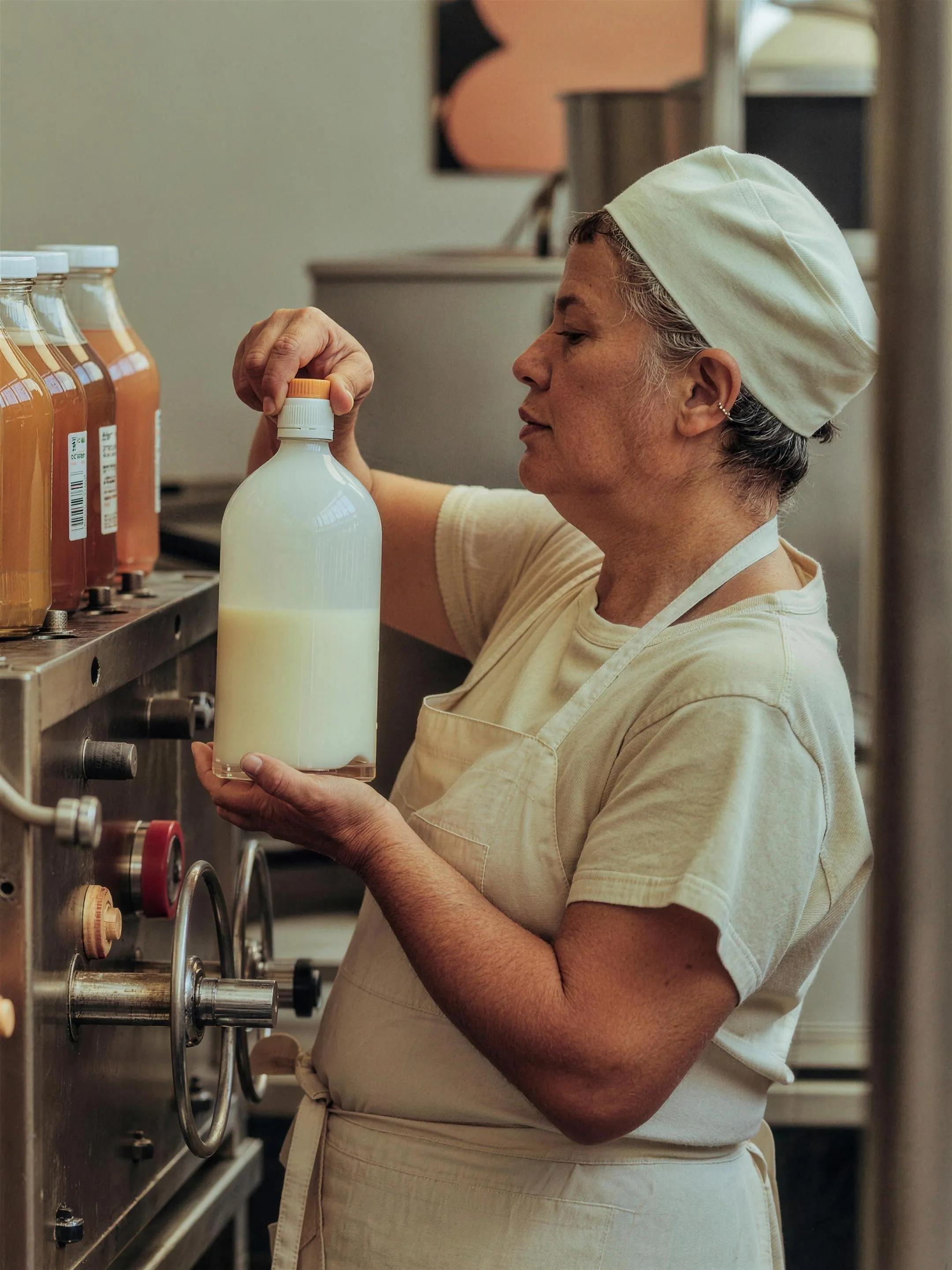 Worker inspecting a filled bottle on a beverage production line