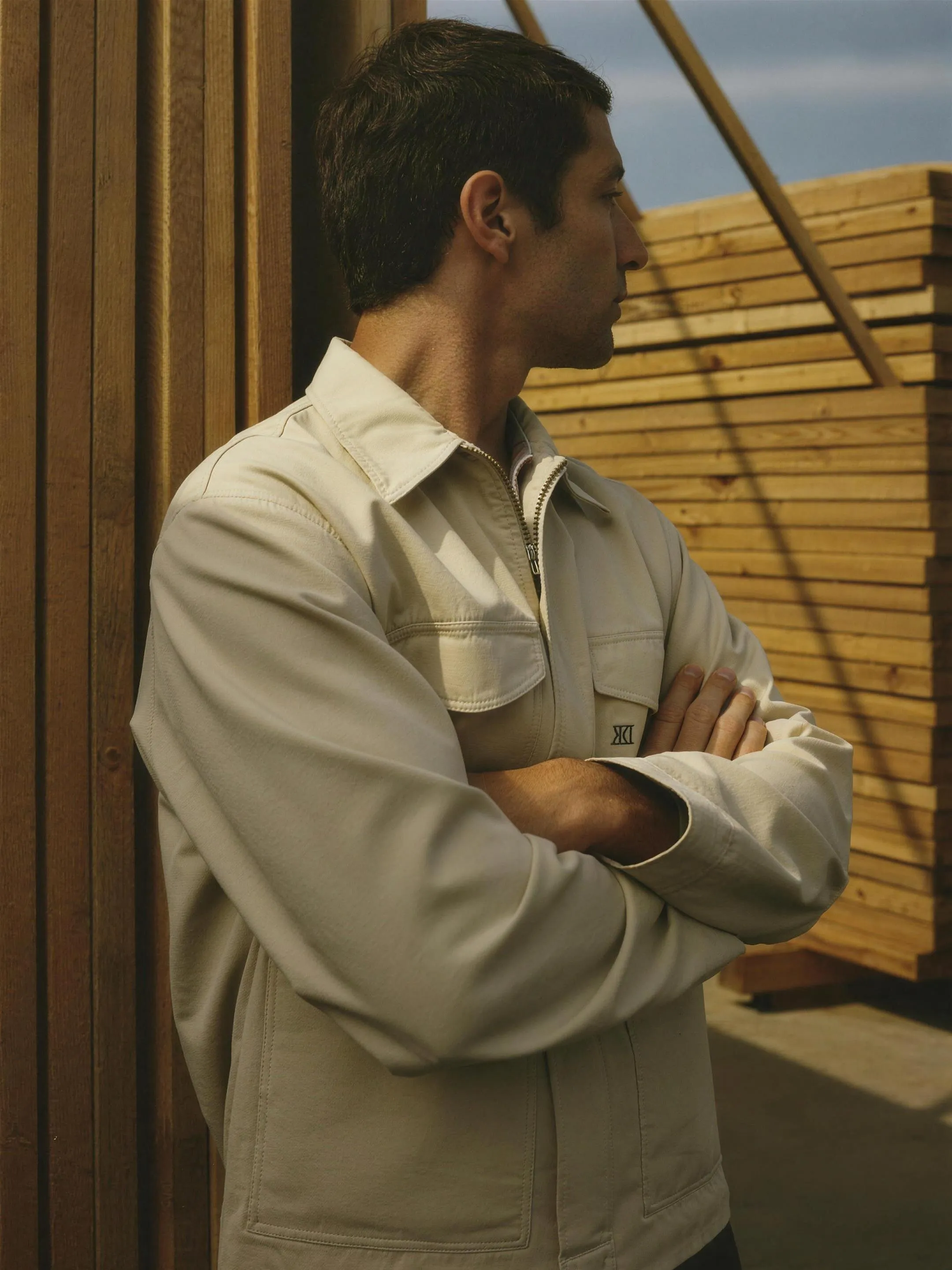Worker standing beside stacked timber in a building products yard