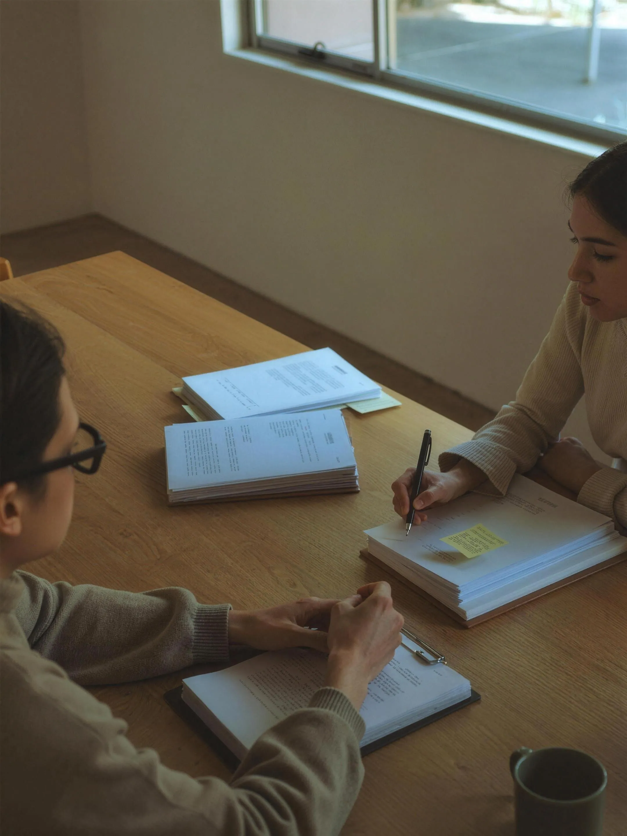 Two colleagues reviewing contract documents across a desk