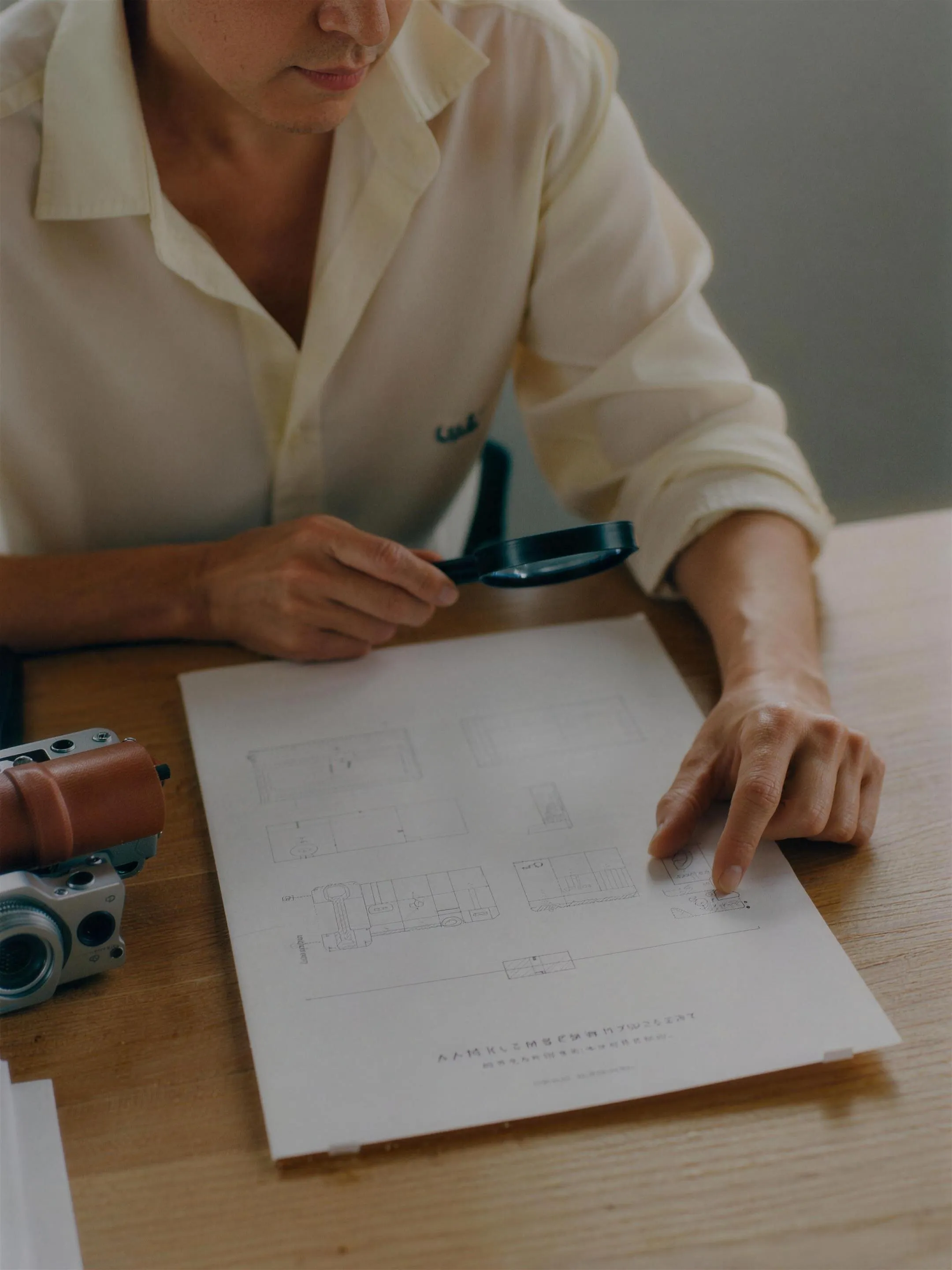 Hands smoothing a large technical drawing across a work surface