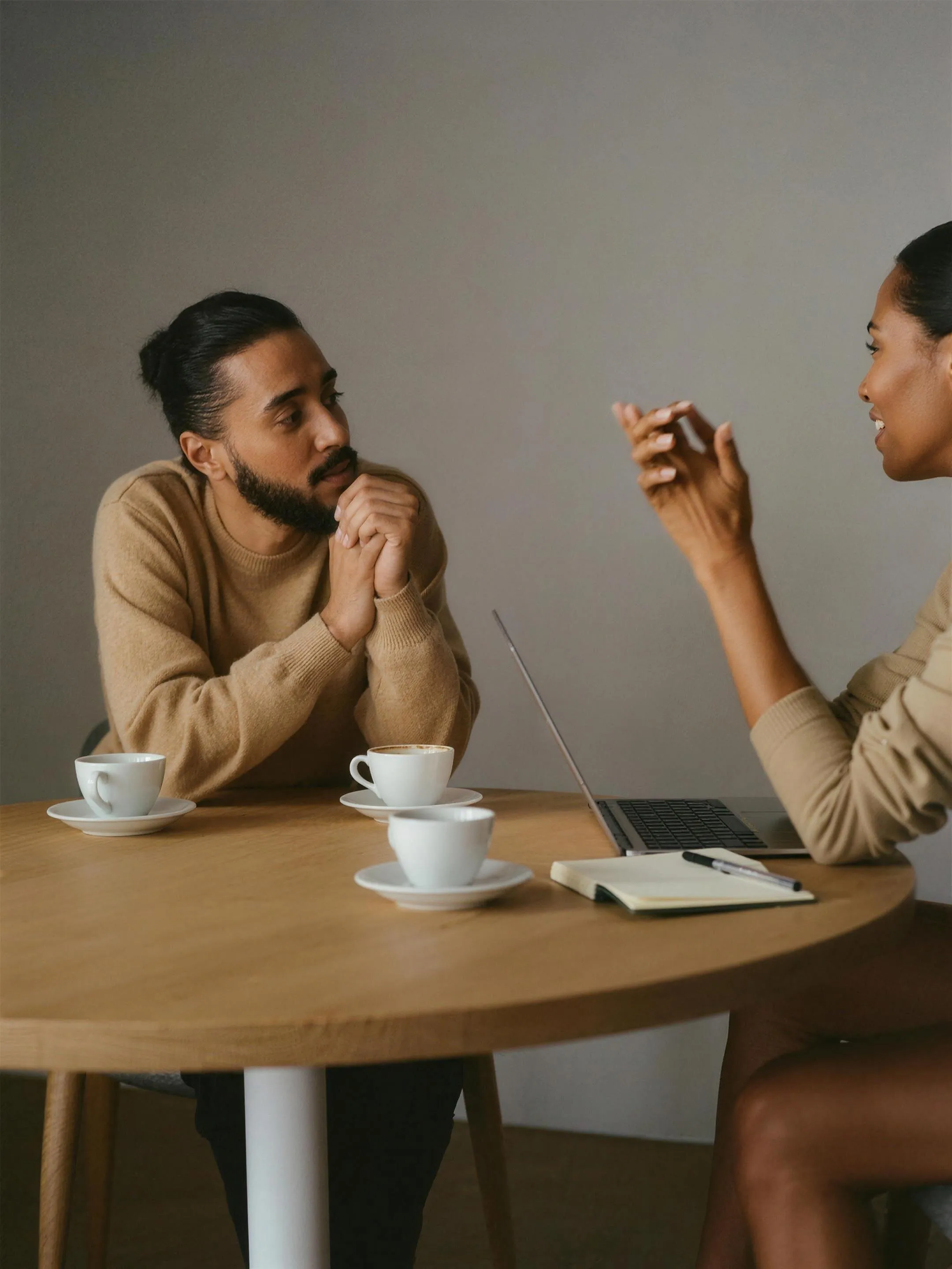 Two people in conversation over coffee at a meeting table