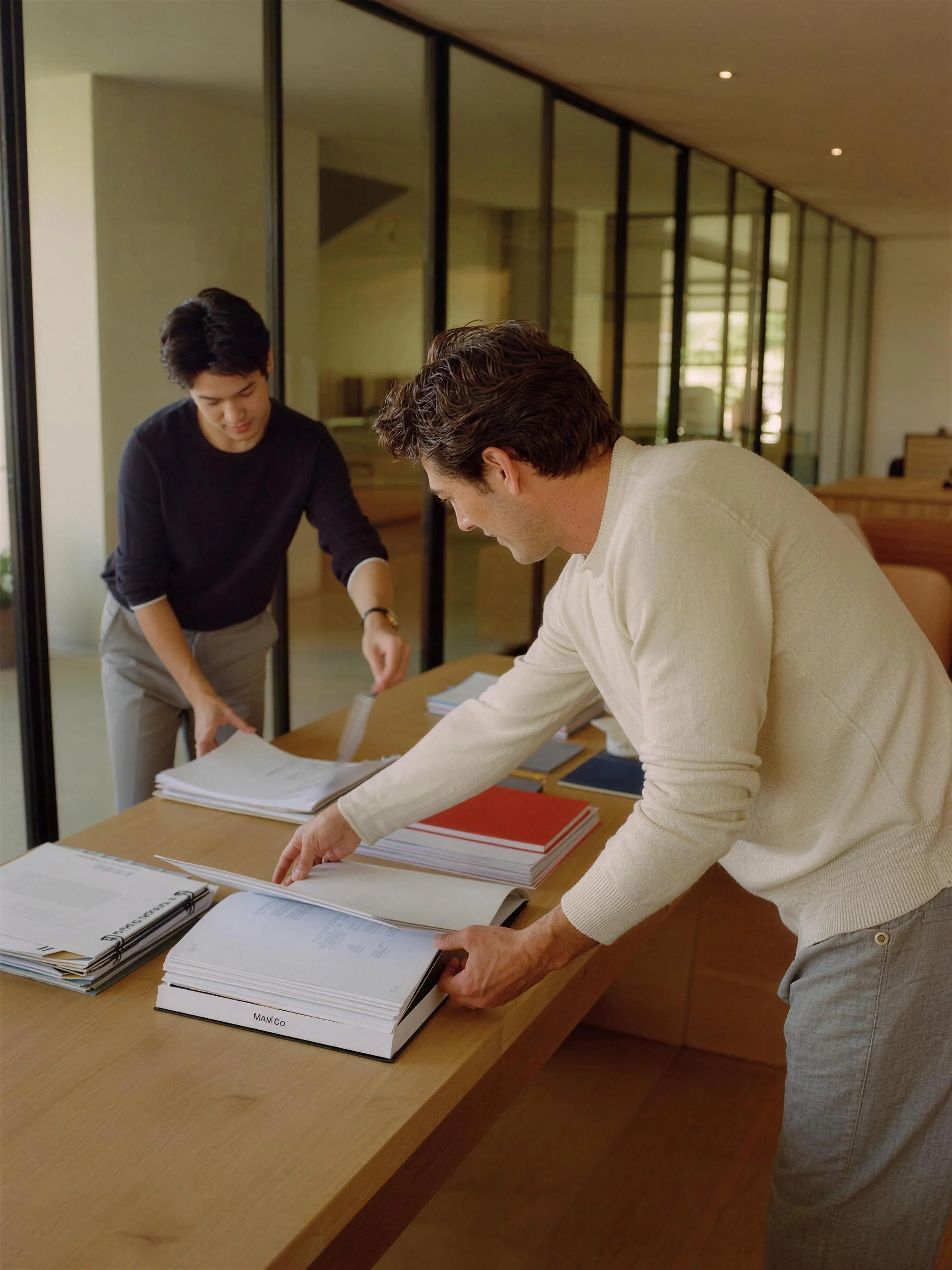 Two colleagues comparing documents at a standing desk