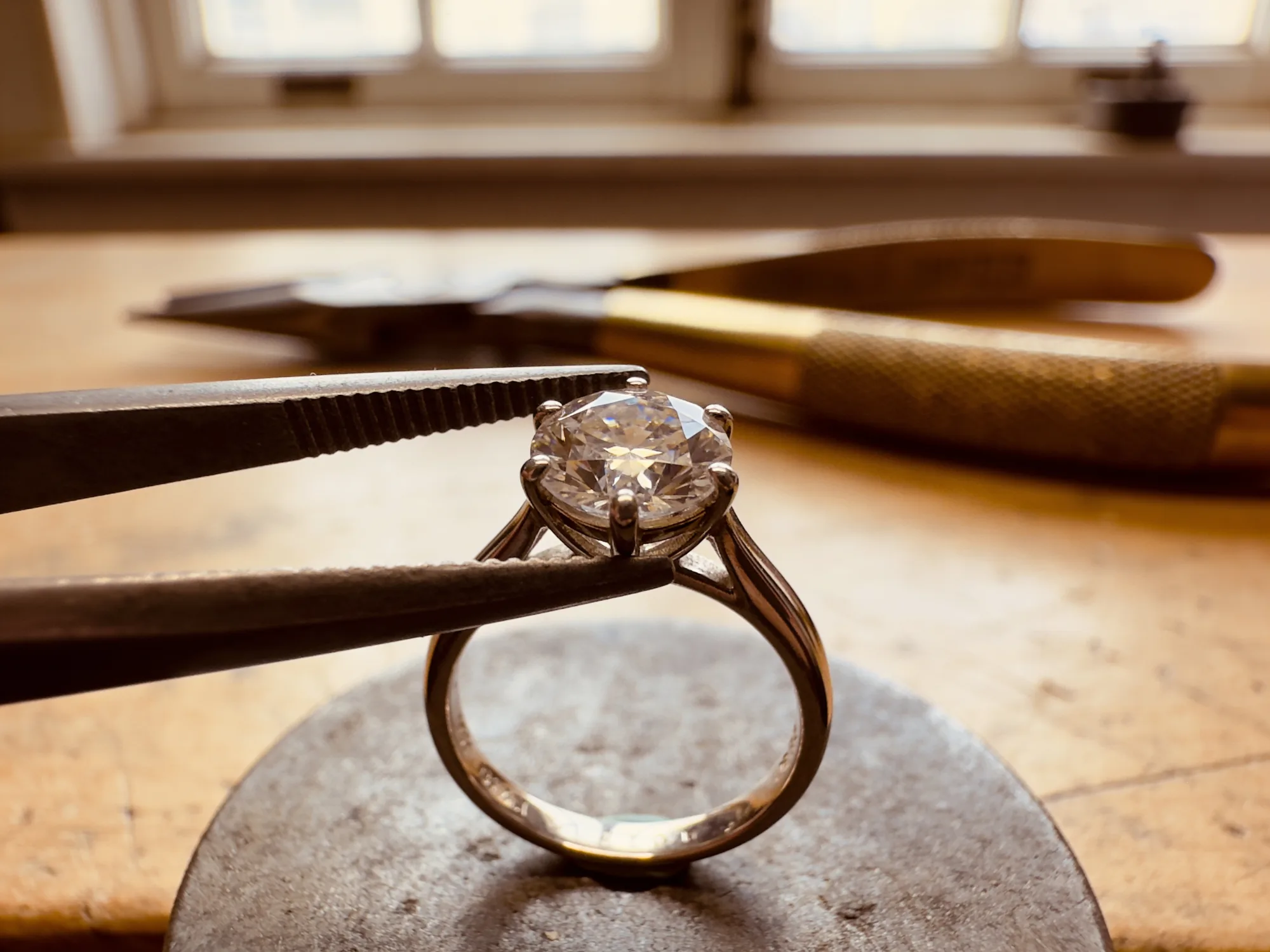 Macro of a diamond ring held in a jeweler's bench prong