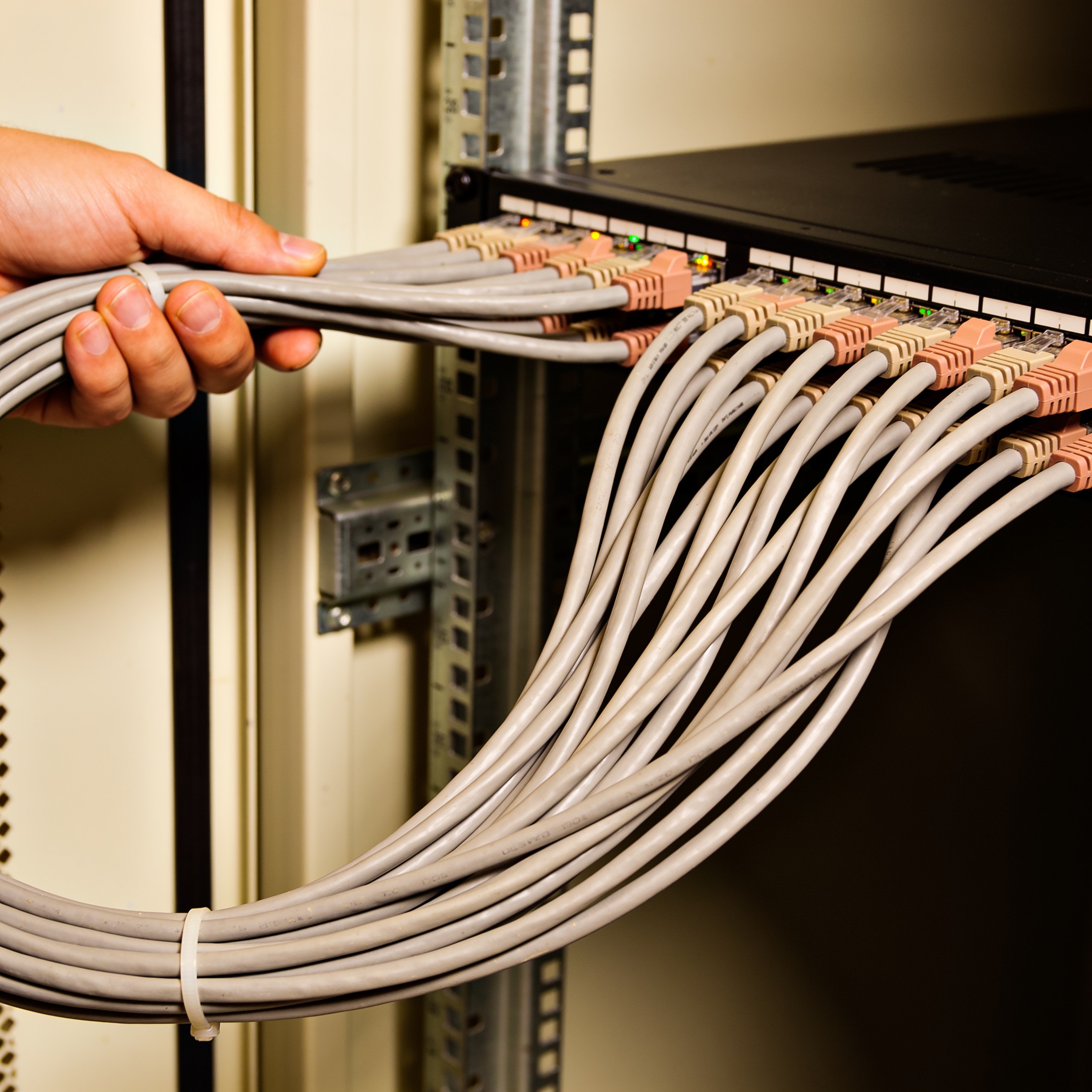 Neatly bundled network patch cables curving into the side of a server rack