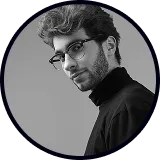 Black and white portrait of a man with glasses and a beard wearing a black turtleneck.