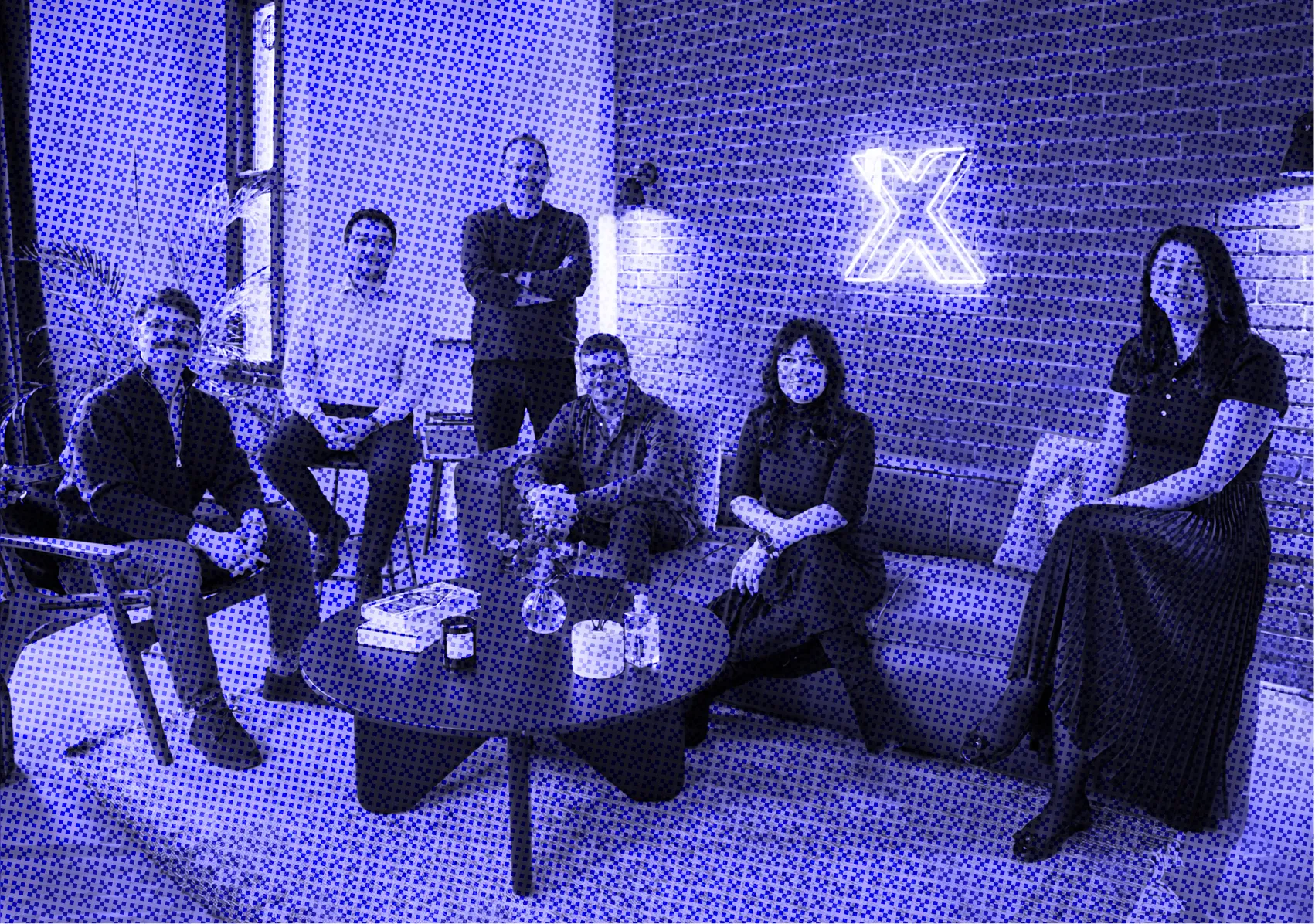 People sitting and standing around a coffee table in a modern living room setting.