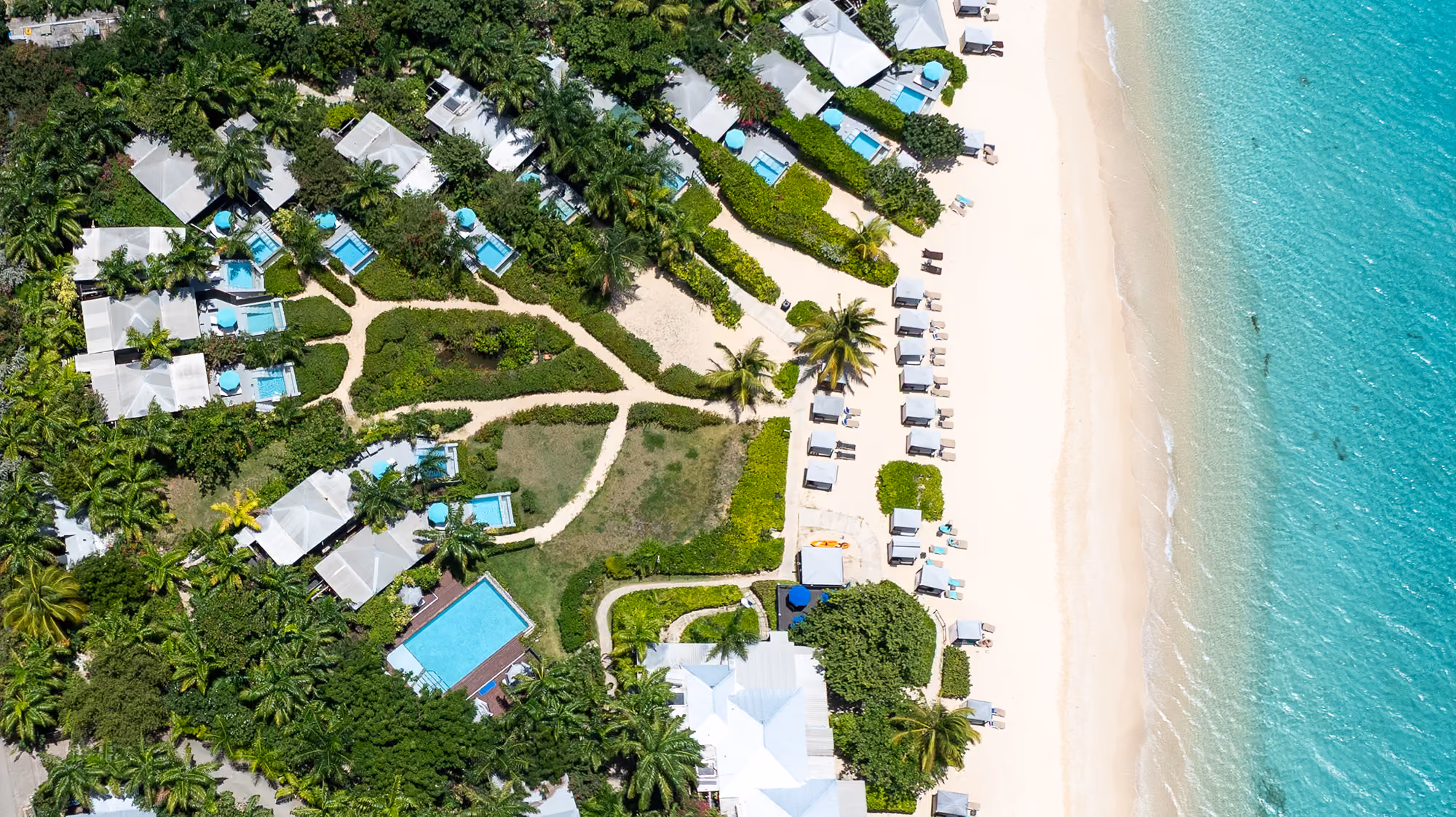 Aerial view of Keyonna Beach Resort plunge pool cottages beside white sand beach, Antigua