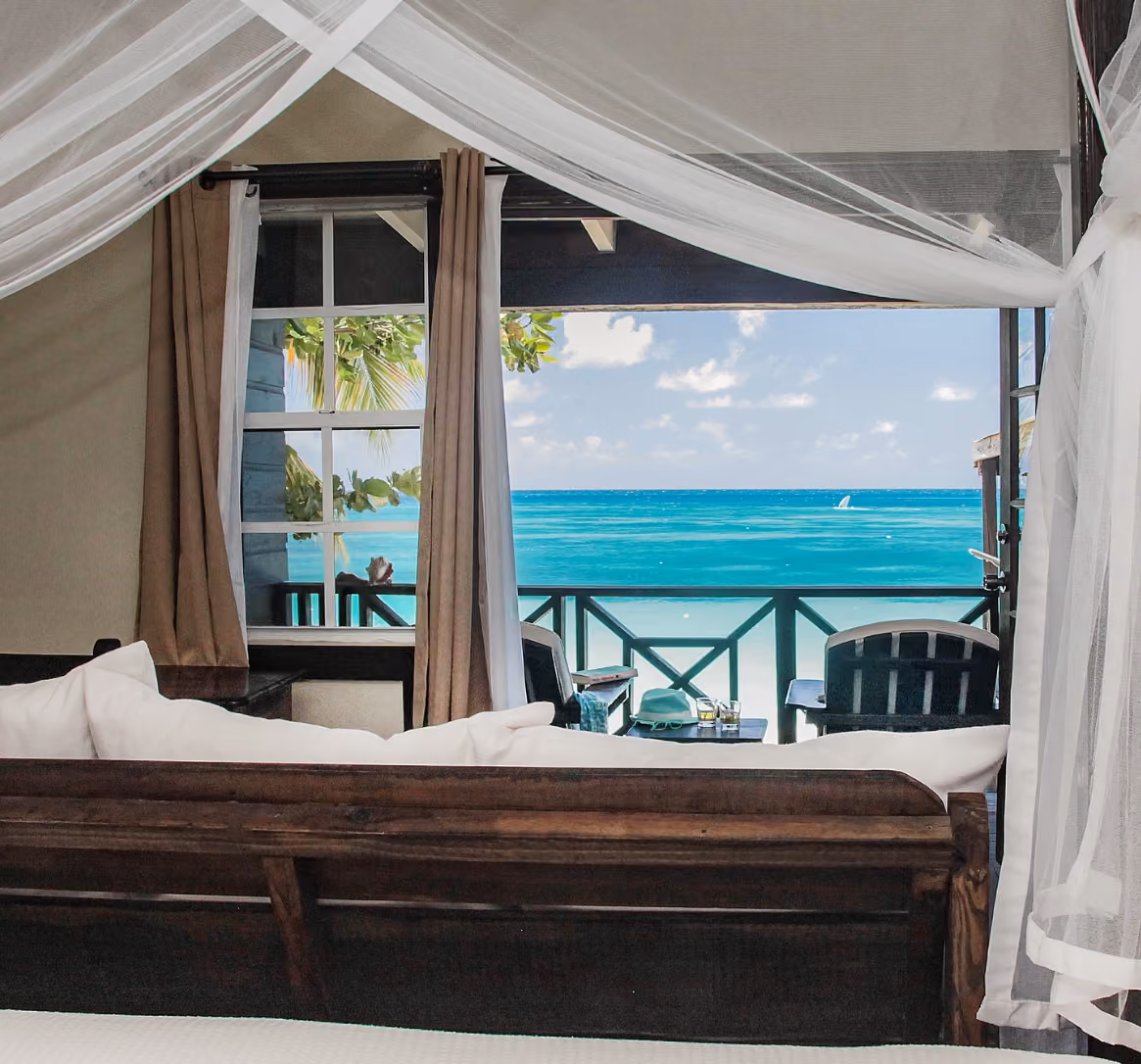 Cottage bedroom opening onto a private veranda with views of the Caribbean Sea