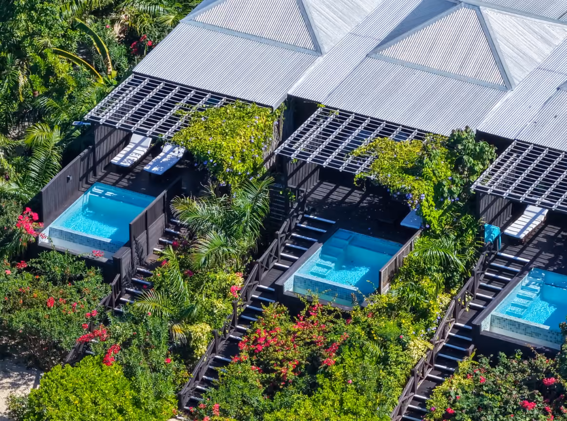 Aerial view of cottages with plunge pools nestled among tropical trees