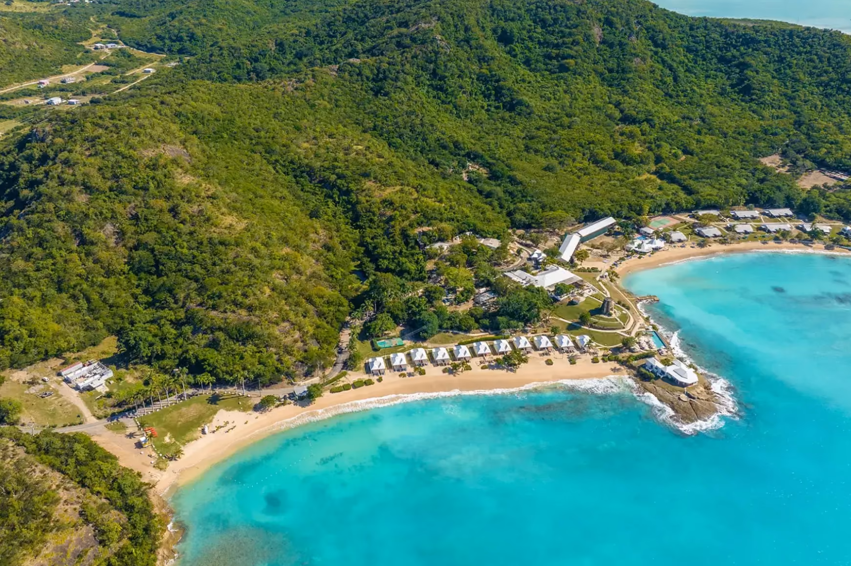 Aerial view of Hawksbill's curved beach and green hillside on the Antiguan coast