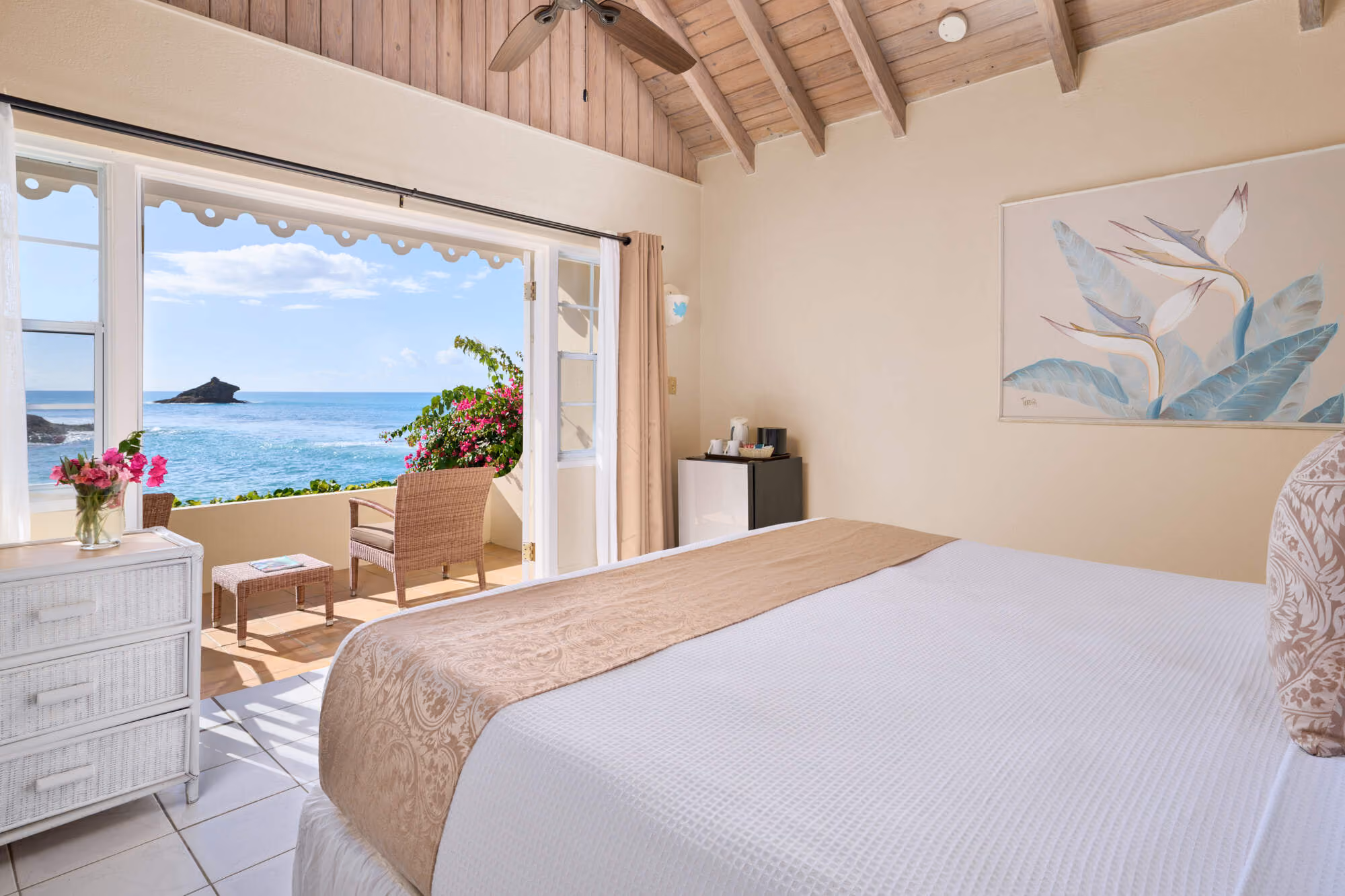 Cottage bedroom with vaulted timber ceiling opening onto a sea-view balcony, Hawksbill