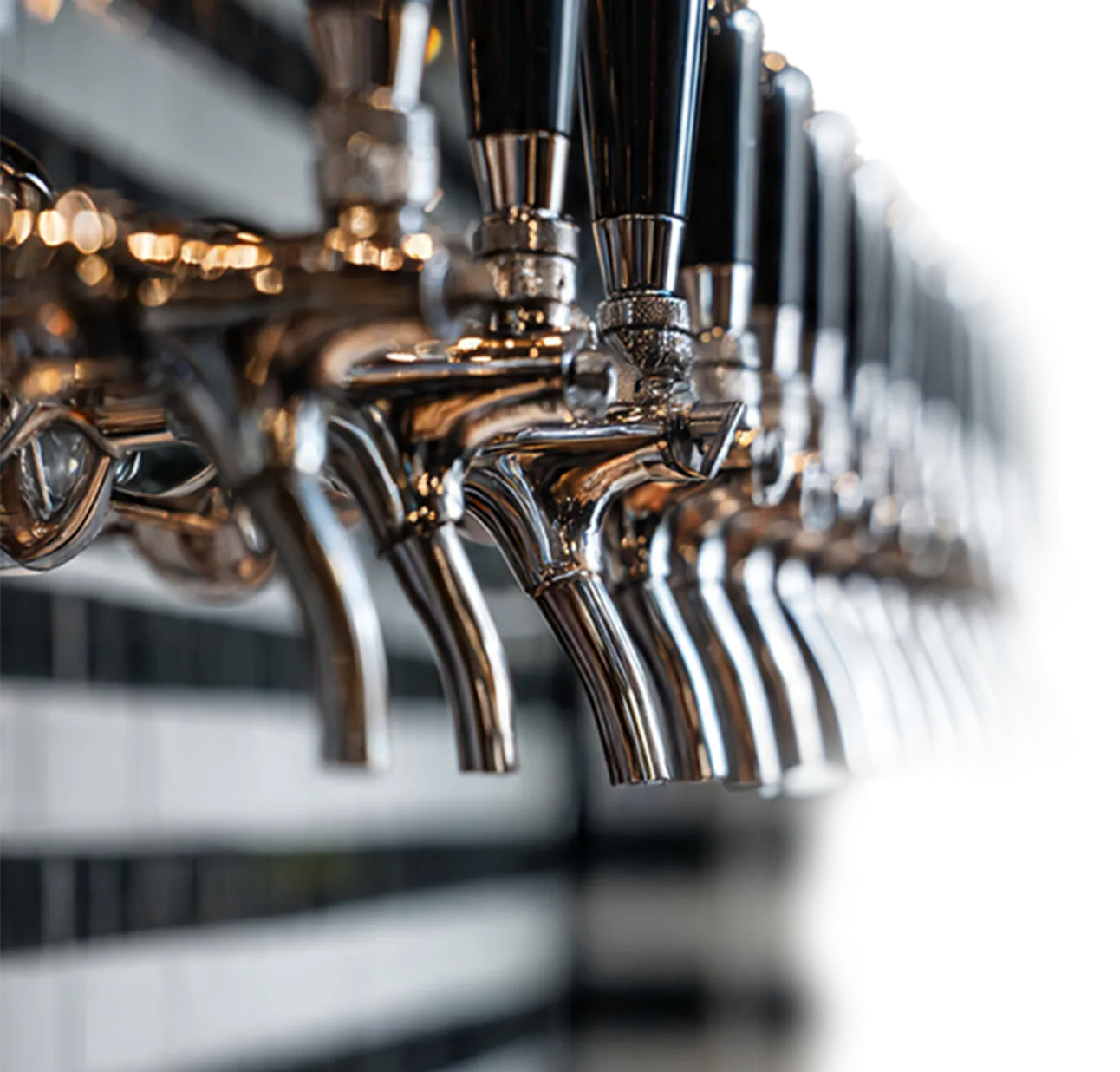 Rangée de robinets de bière en acier inoxydable avec poignées noires dans un bar moderne.