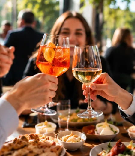 Trois personnes trinquent avec un verre d'apéritif orange et un verre de vin blanc.