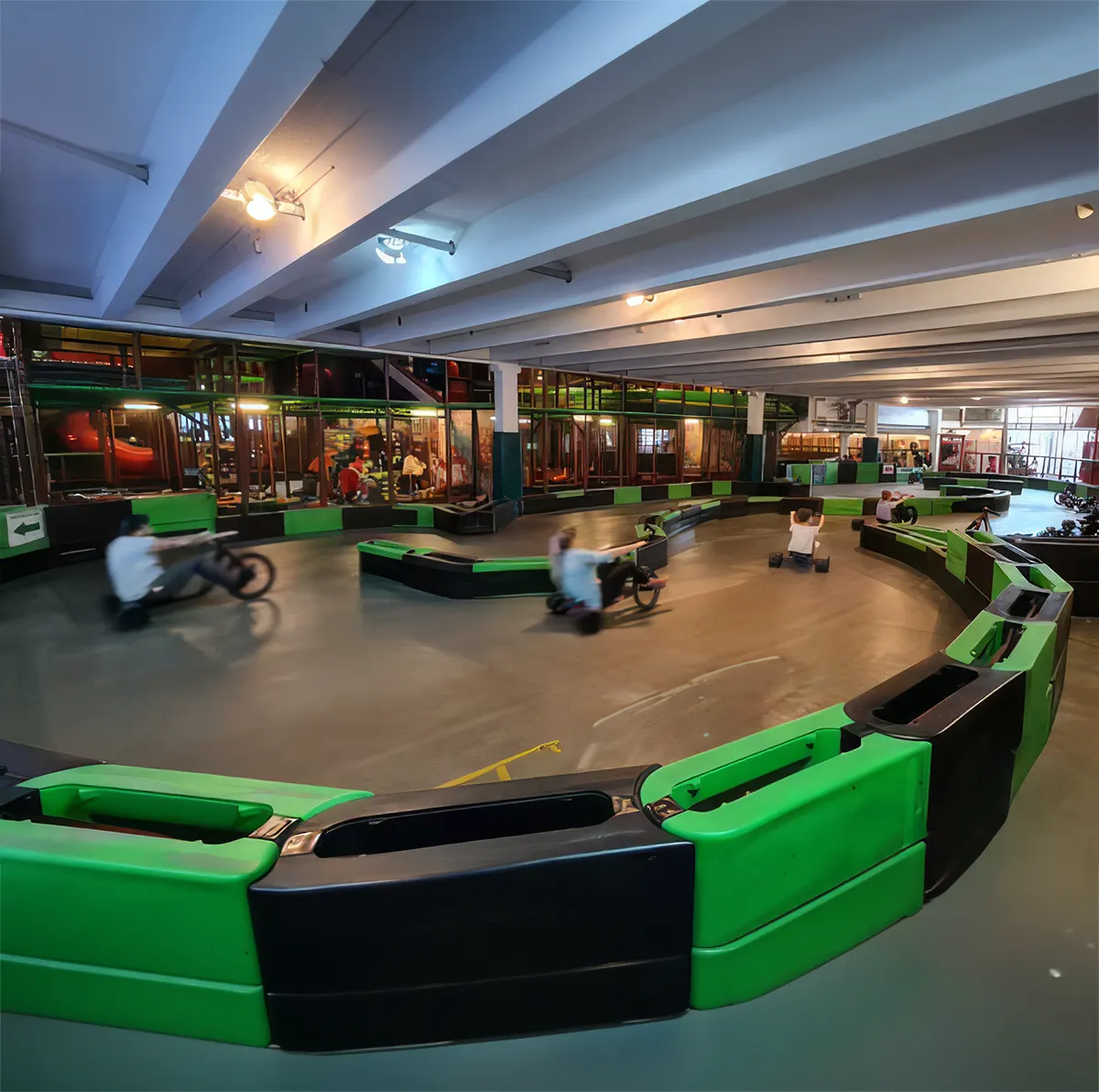 Kinder fahren auf einem abgetrennten Drift-Bike-Rundkurs in einer Indoor-Freizeitarena.