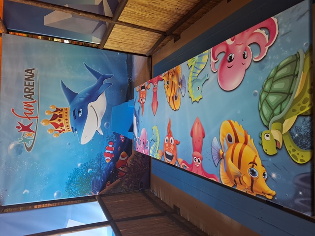 Bunter Tisch mit Meeresbewohnern vor Wand mit Hai und Schriftzug Fun Arena.