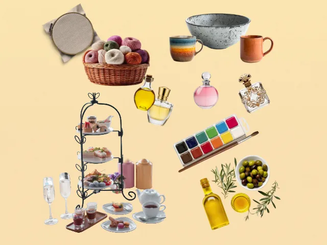 Square-cropped flat lay of the same gift objects: embroidery hoop, ceramic mugs and bowl, perfume bottles, watercolor paints, afternoon tea stand, and olive oil with olives.