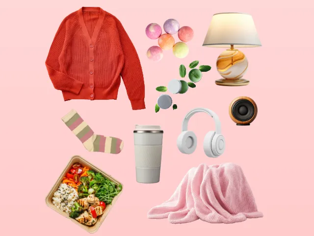 A cropped flat lay of baby shower gift items on a pink background, including an orange cardigan, bath bomb spheres, mint balm tins, a table lamp, striped socks, an insulated tumbler, headphones, a speaker, a meal container, and a pink blanket.