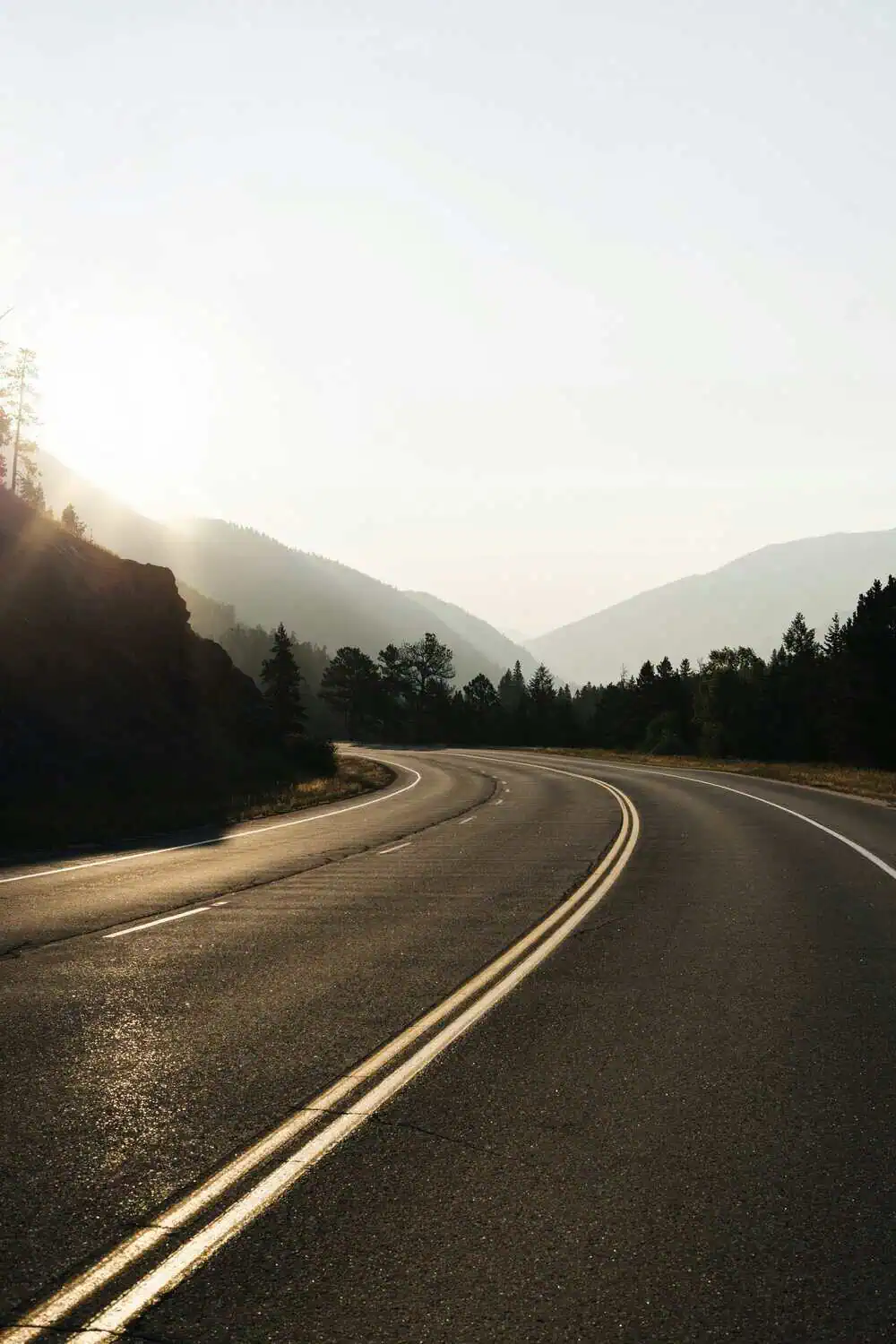 A hardcover scenic drives guidebook on a coffee table with a mountain road on the cover.