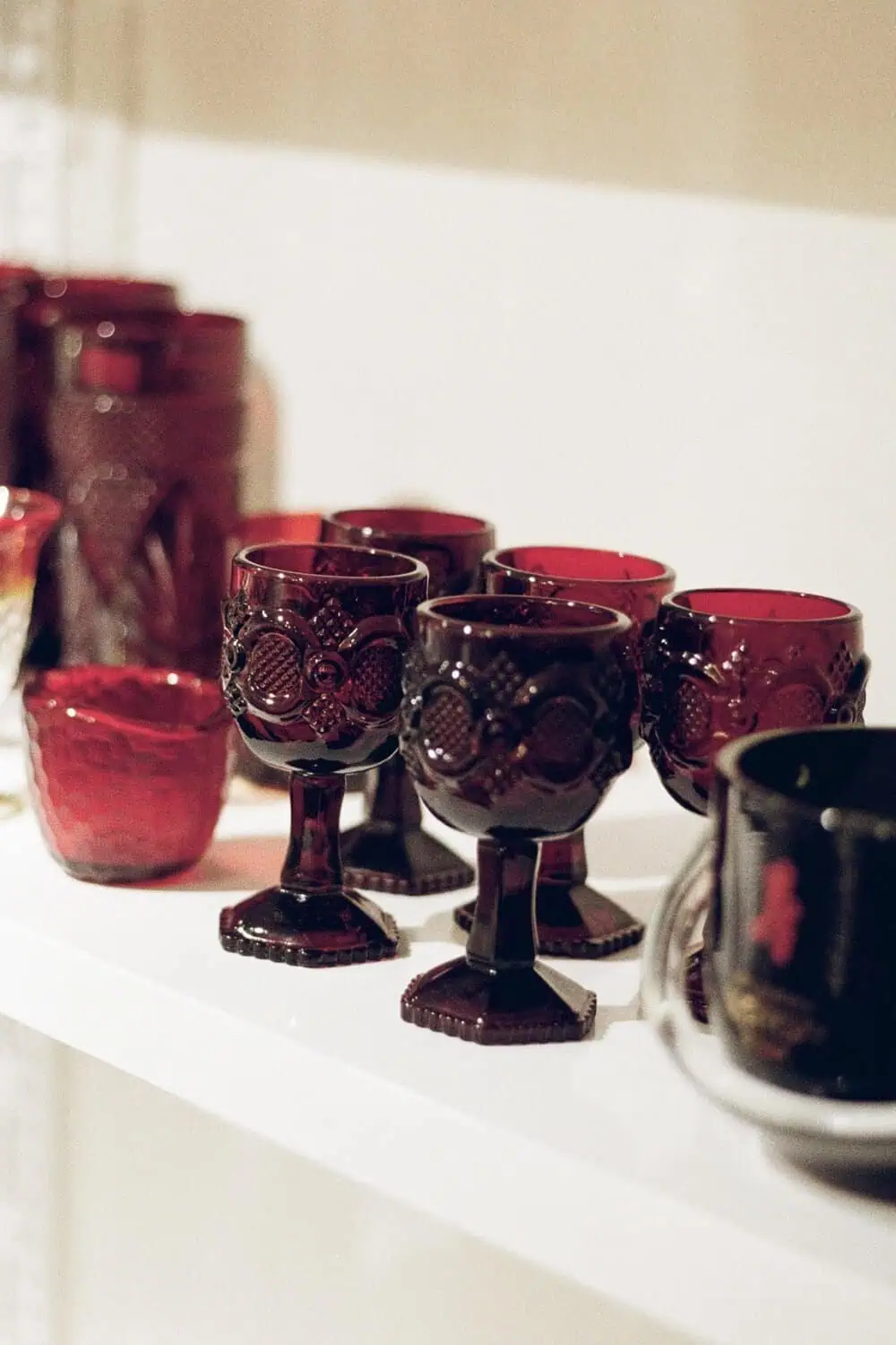 Ruby-red glass tumbler pair on a wood table, catching the light.