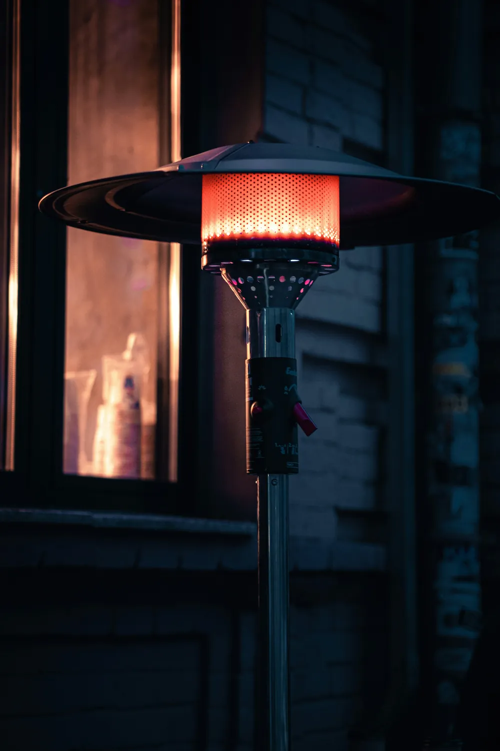 A wall-mounted patio heater glowing on a porch at dusk.