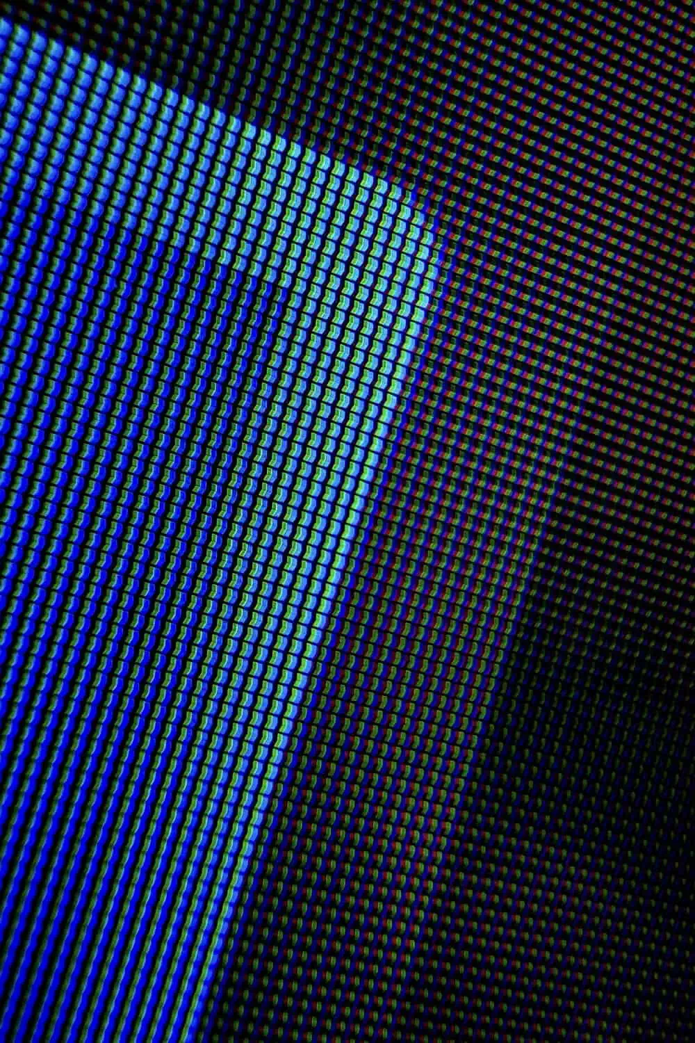 An extreme close-up of a glowing pixel display shows individual blue and green LED squares blending into a soft gradient.