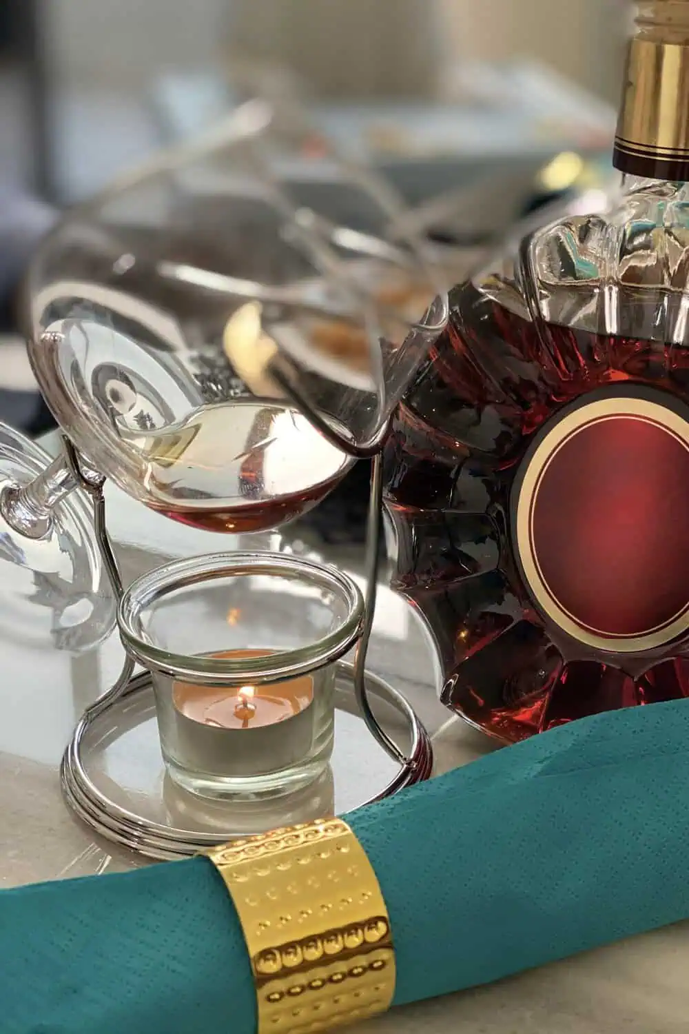 Brandy is poured into a glass balanced over a tabletop warmer stand lit by a small candle.
