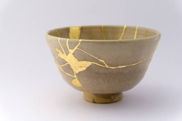 A ceramic bowl repaired with gold kintsugi seams, symbolising beauty found in what's been broken and mended