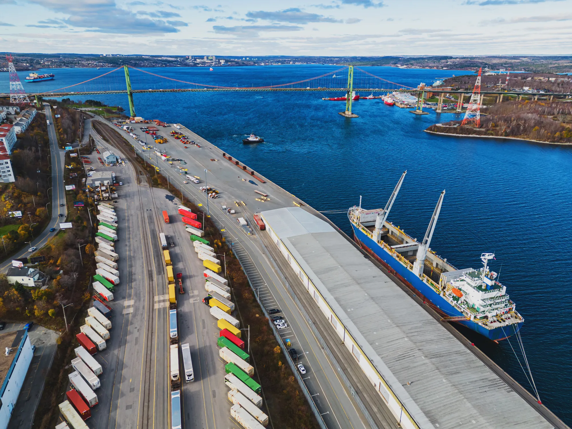 Aerial view of cargo ship docked at port with container trucks.