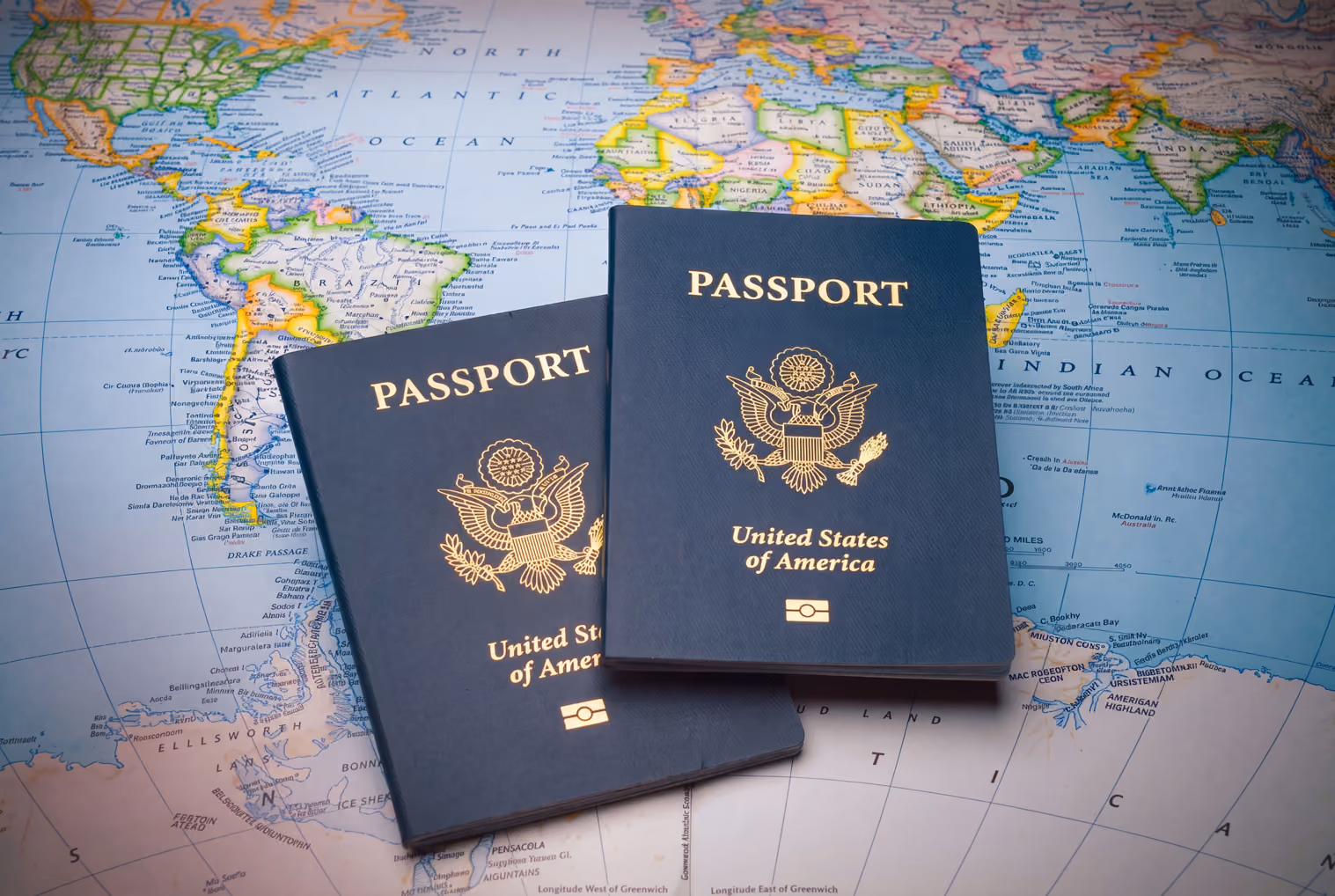 Two United States passports on a world map showing the Americas and part of Africa and Europe.