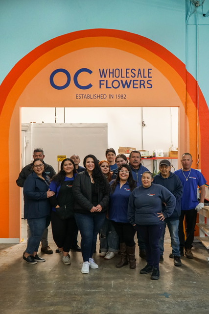OC Wholesale Flowers team standing beneath the Established in 1982 entrance arch
