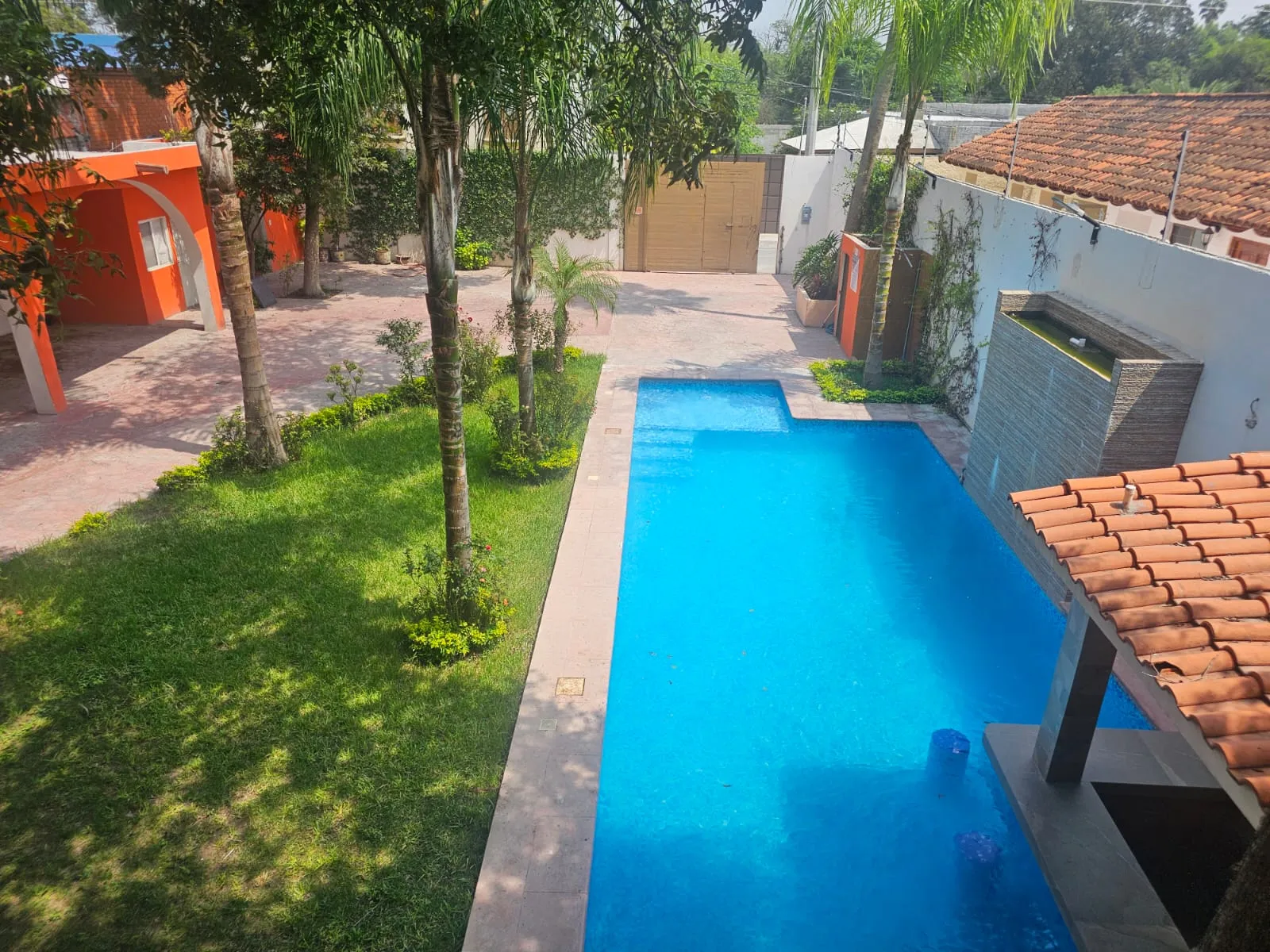 Alberca, jardín y fachada naranja del Hotel Los Arcos Inn en García