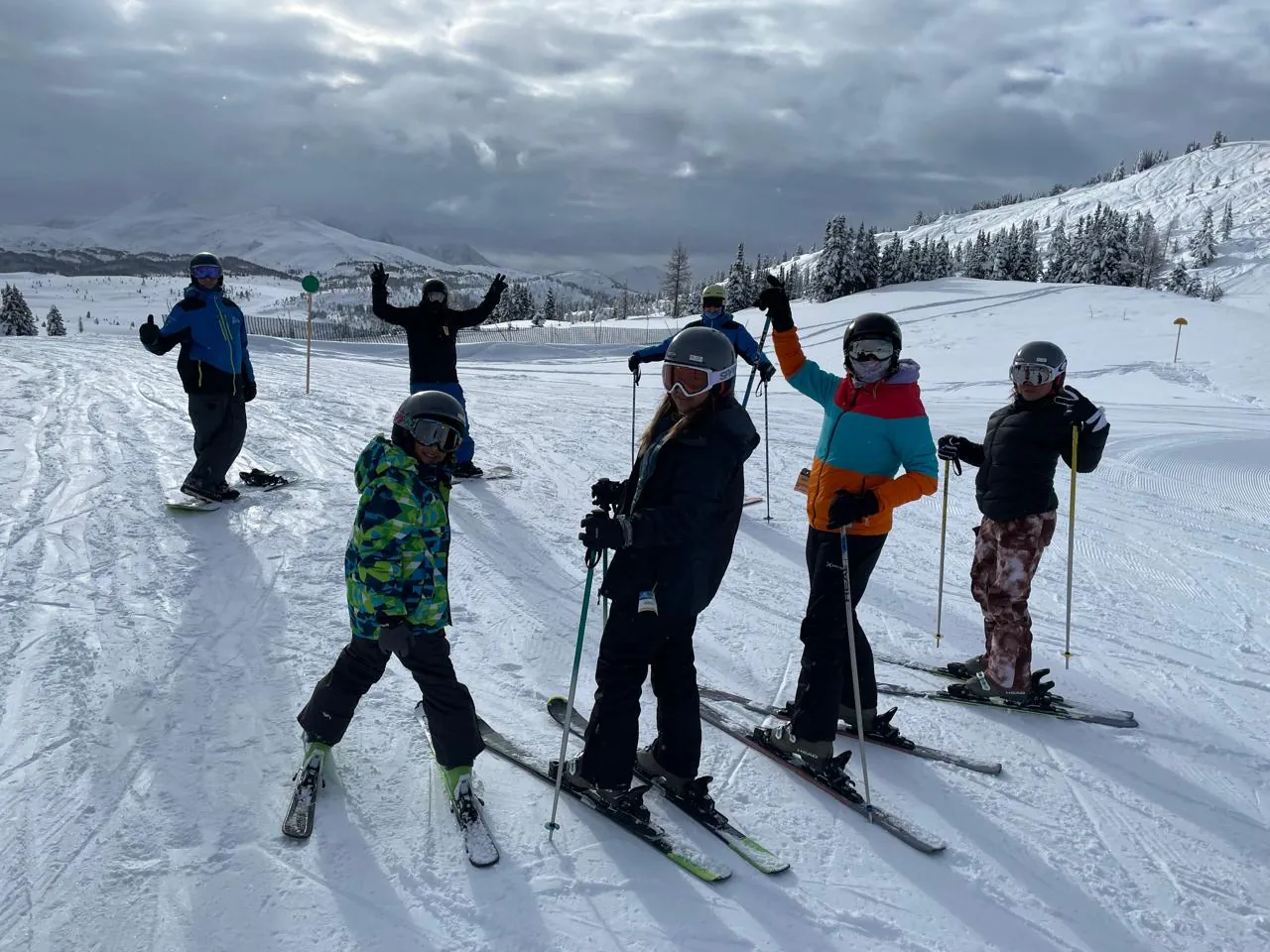 Grupo del club TerritorioSnow esquiando en pista con montañas nevadas de fondo
