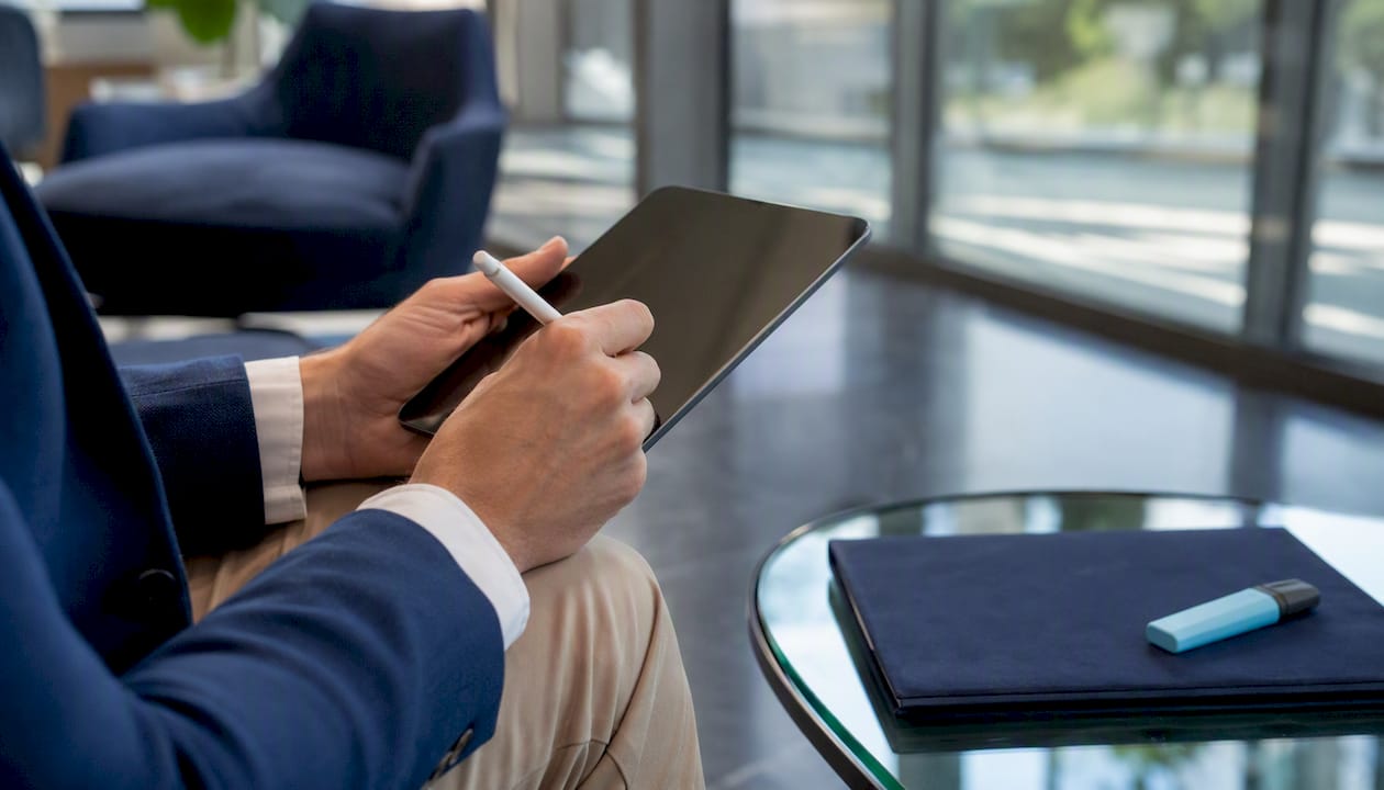 Hands with stylus over tablet in office