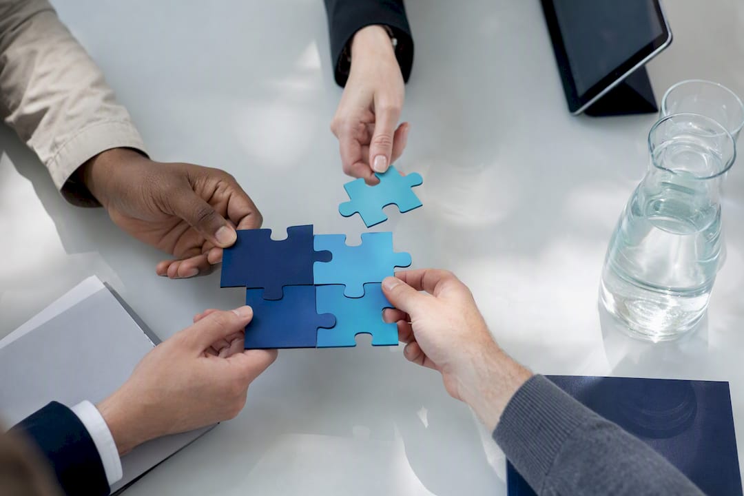 Hands assembling puzzle pieces representing collaboration