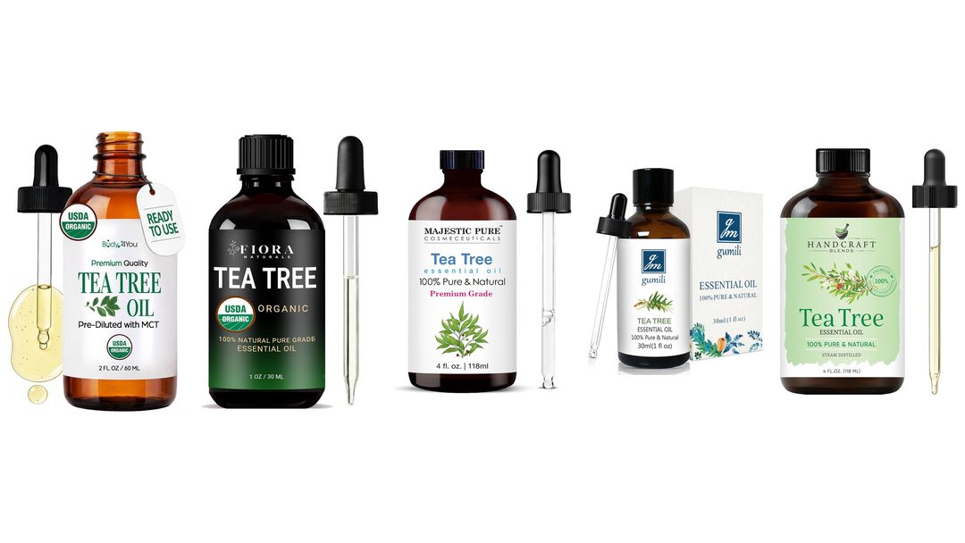 Five dark glass tea tree essential oil bottles with glass droppers and one green box on white