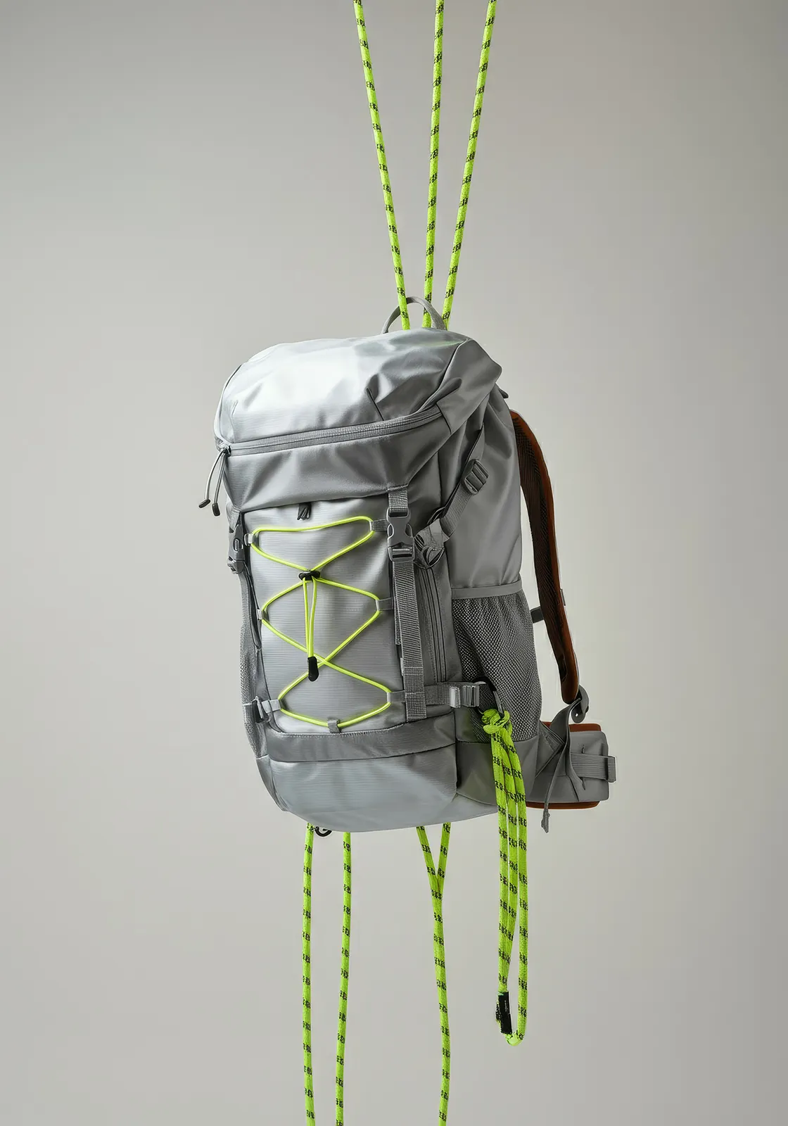 Gray backpack with neon green cords suspended by neon green ropes against a plain background.