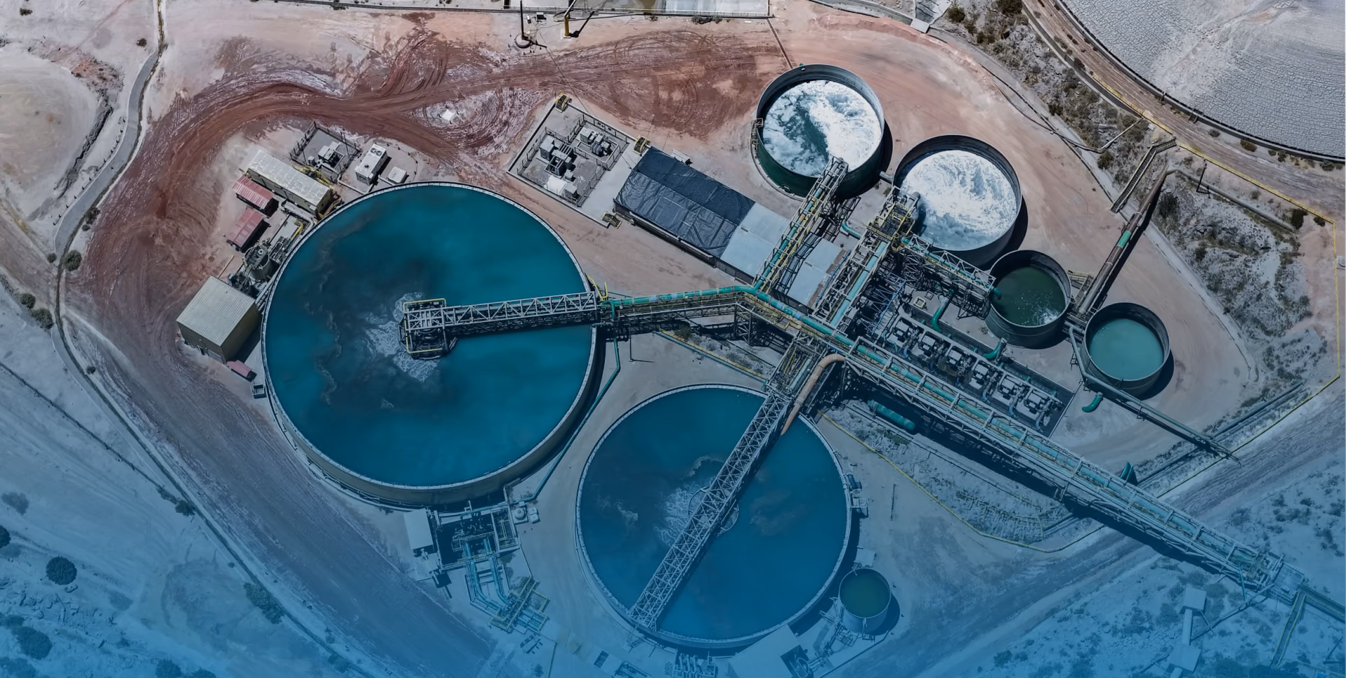 Aerial view of a wastewater treatment plant with large circular tanks holding blue and green water.