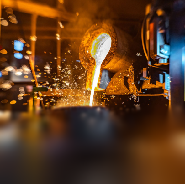 Molten metal pouring from a furnace spout with sparks flying in a foundry.