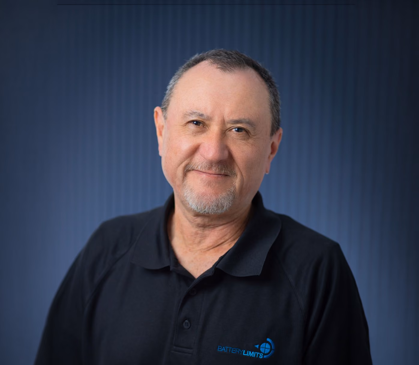 Smiling middle-aged man with short hair and goatee wearing a black polo shirt with a blue logo.