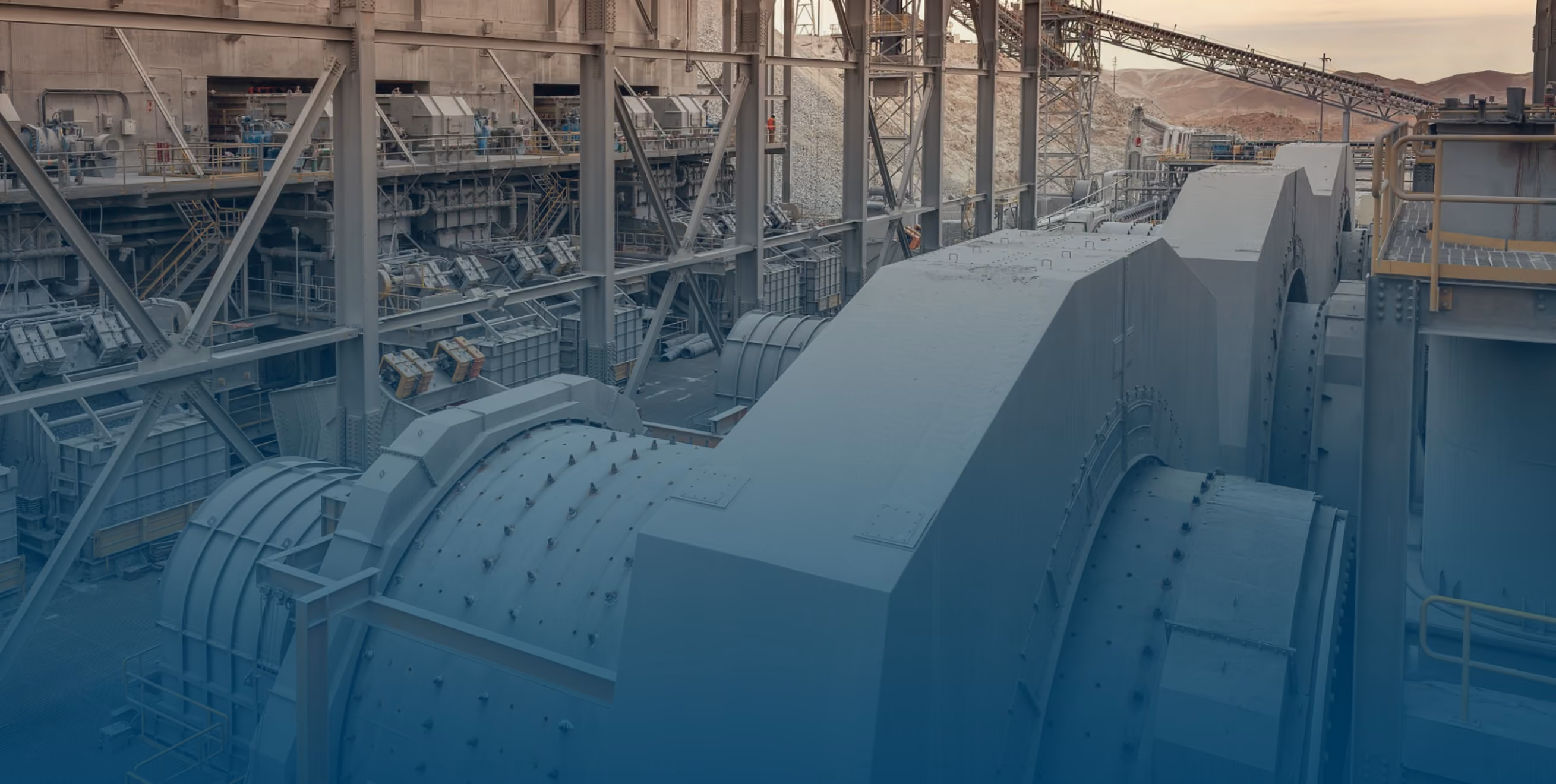 Large industrial machinery inside a factory with metal structures and conveyor belts in a desert setting.