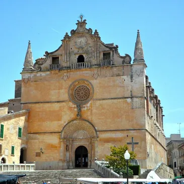 Historic stone church with a large circular stained glass window and two towering spires on a sunny day Image.