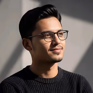 Man with glasses and short black hair, wearing a black sweater, facing right with a slight smile.