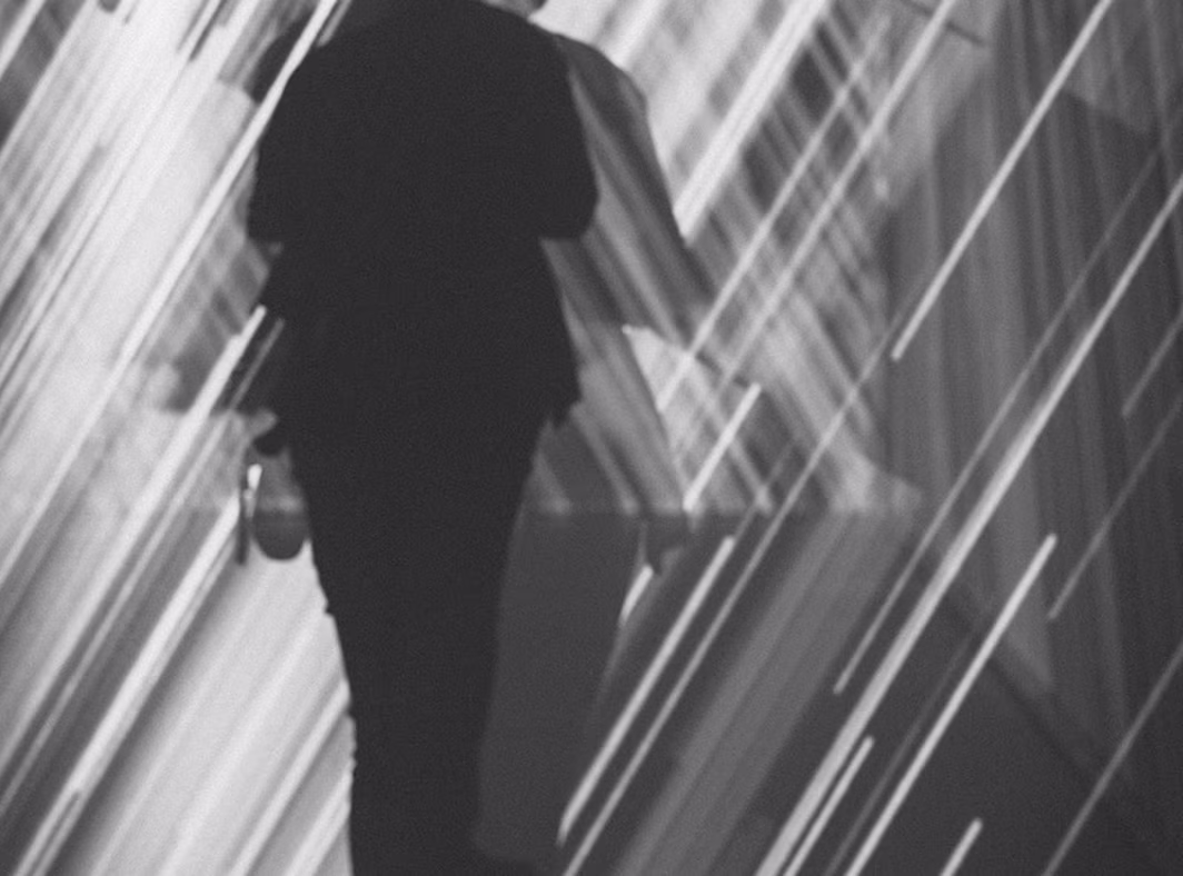 Monochrome silhouette of a person walking through light streaks, representing digital process transformation