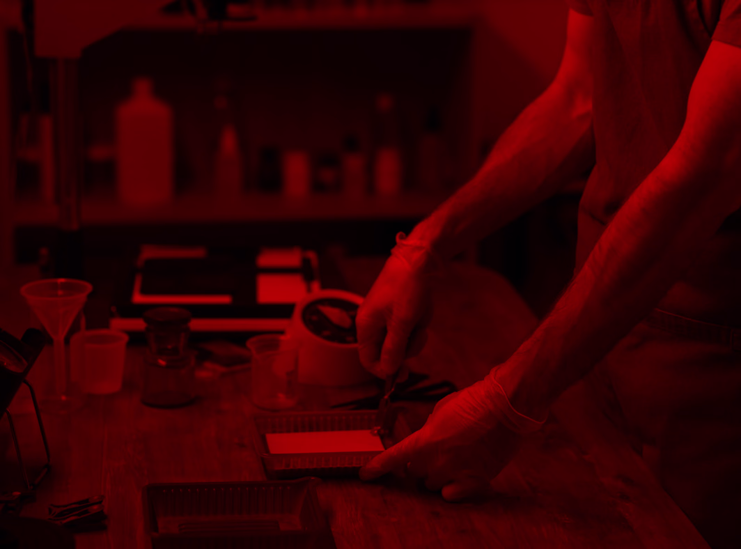 Hands adjusting design elements on a workspace bathed in red ambient light