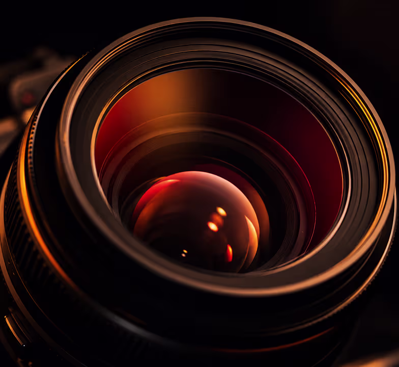 Close-up of a camera lens reflecting warm amber and red gradient light