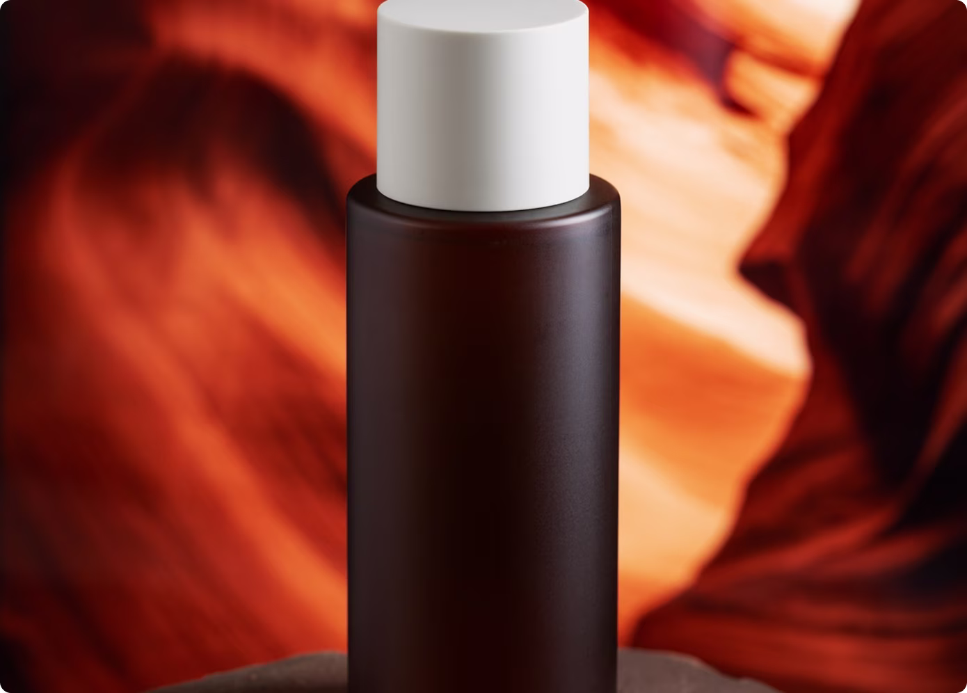 Minimalist cosmetic bottle with warm amber lighting and blurred abstract background