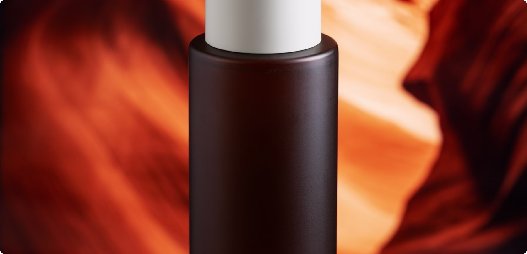 Minimalist cosmetic bottle with warm amber lighting and blurred abstract background