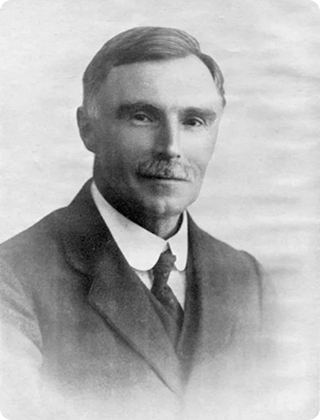 Black and white portrait of a man with a mustache wearing a suit and tie.