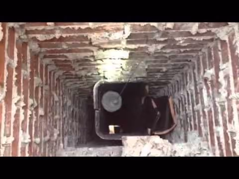 Top view inside a brick chimney flue showing cracked flue tiles